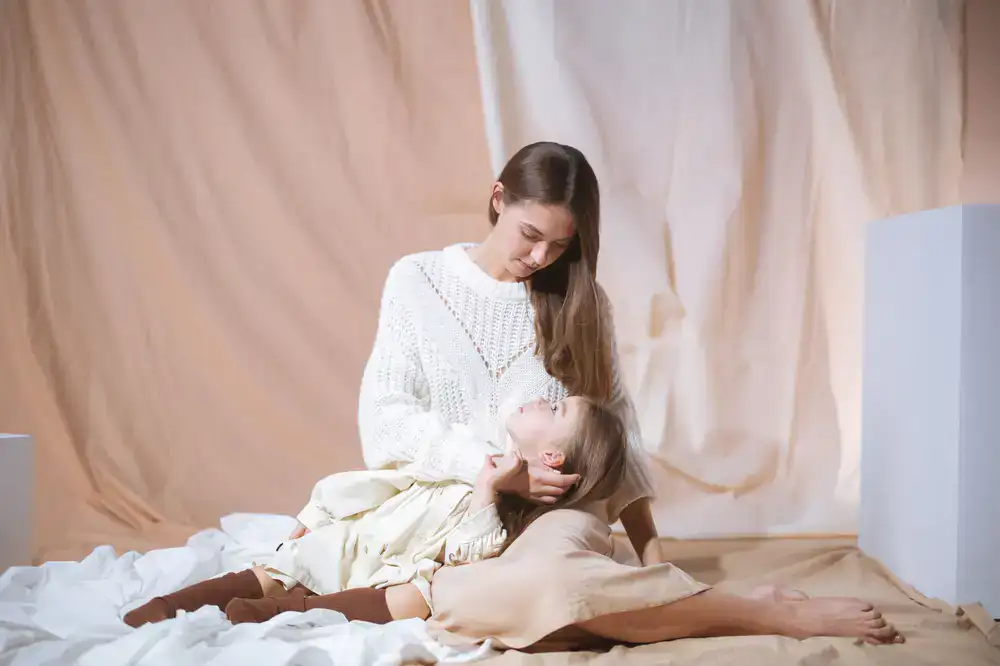 Niña sentada vistiendo un conjunto de punto en tonos beige y blanco